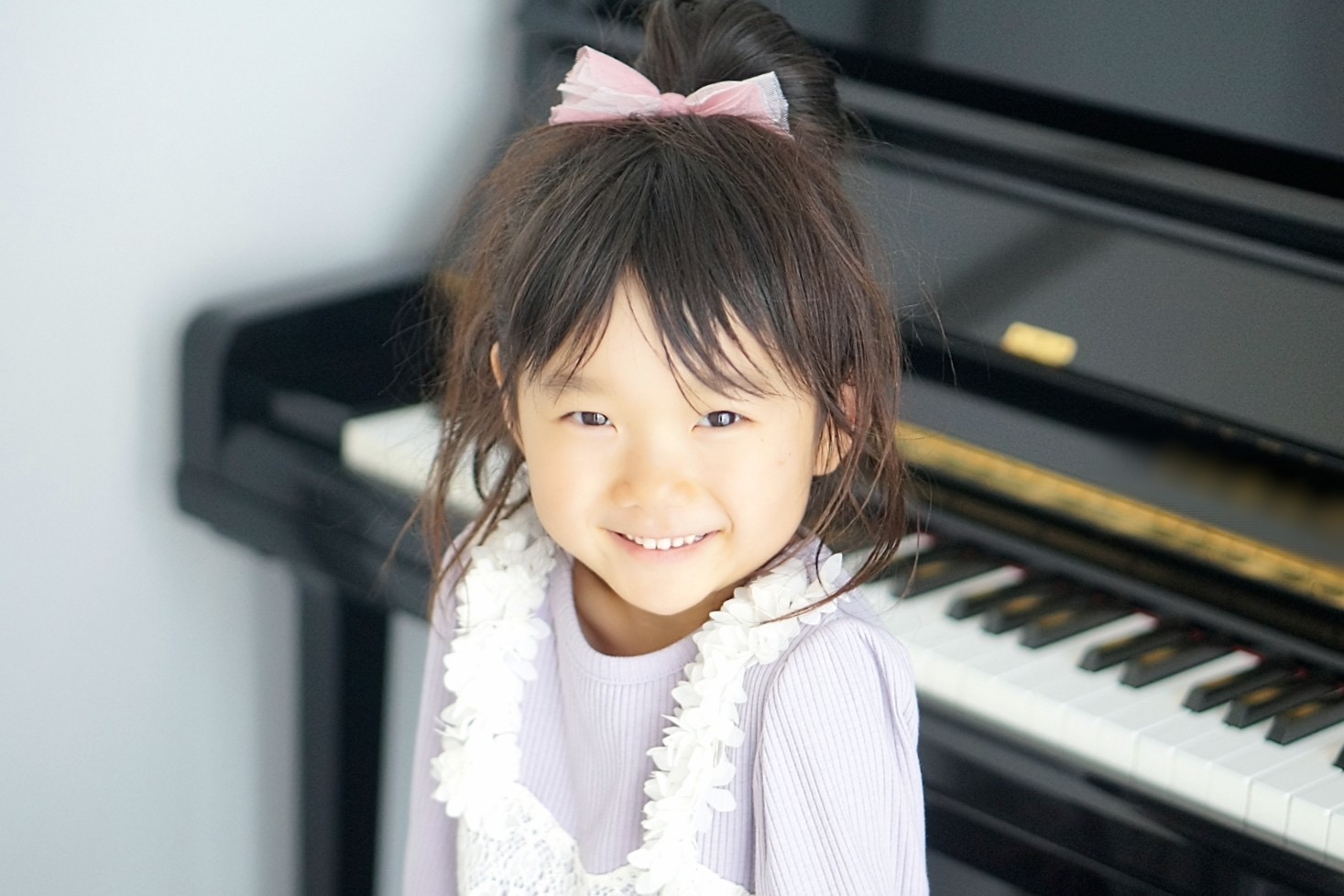 子どもがピアノ前にすわっている画像